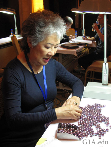Betty Sue examines and sorts loose pearls.